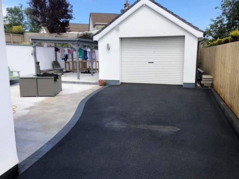 A freshly laid tarmac driveway next to a paved patio in a Dublin garden